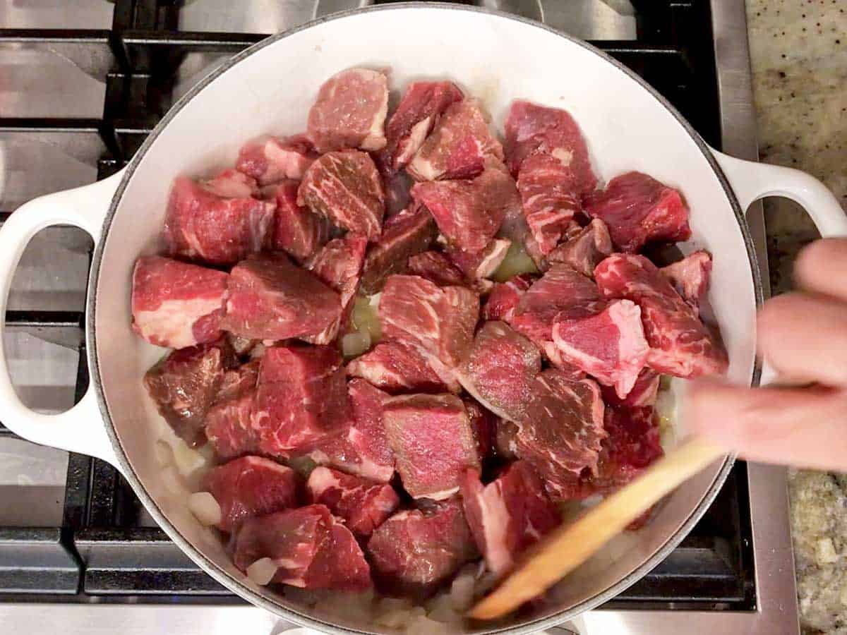 Cooking onions and beef cubes in olive oil.