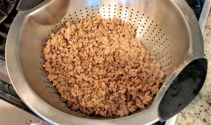 Draining the cooked ground beef.