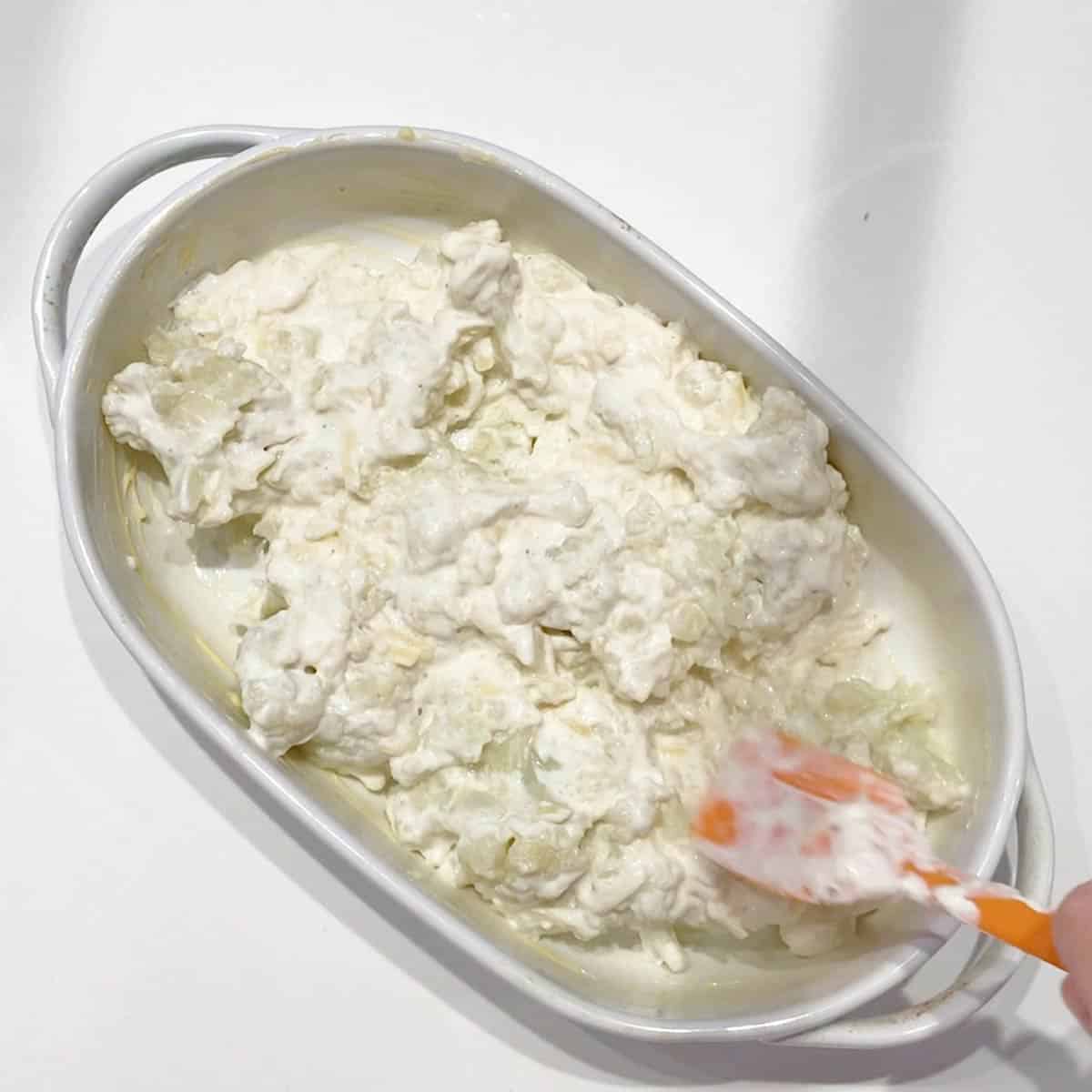 Transferring the gratin mixture to the baking dish.