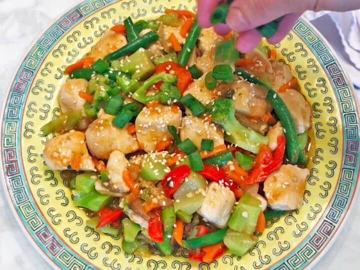 Garnishing the stir-fry with chopped scallions.