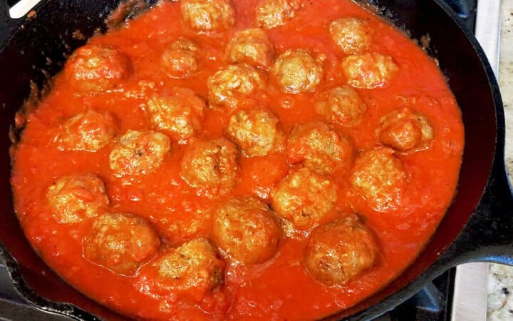 Simmering meatballs in marinara sauce.