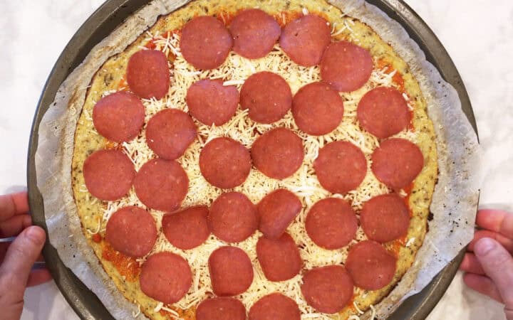 Returning the pizza to the oven after adding the toppings.