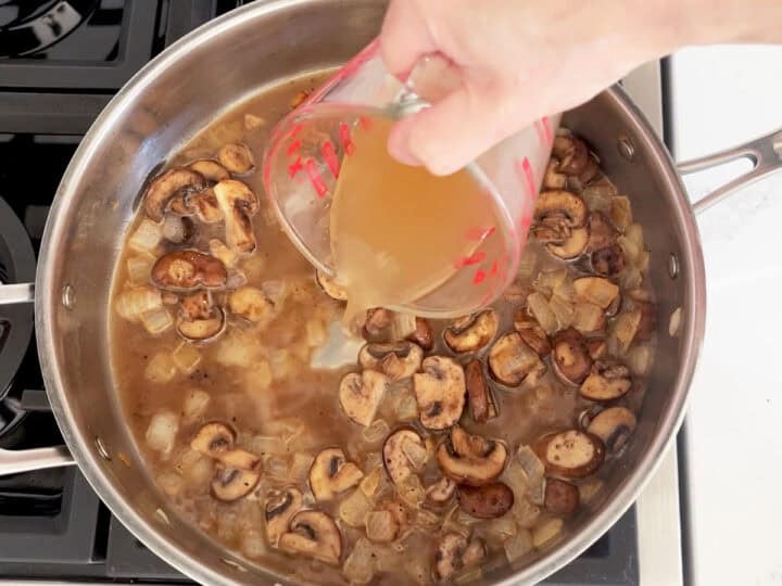 Adding beef broth to the sauce.