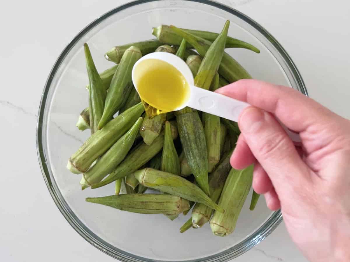 Adding olive oil to the okra.
