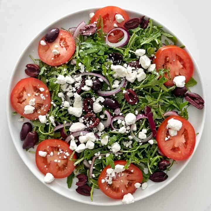 The veggies, olives, and goat cheese were arranged on a plate.