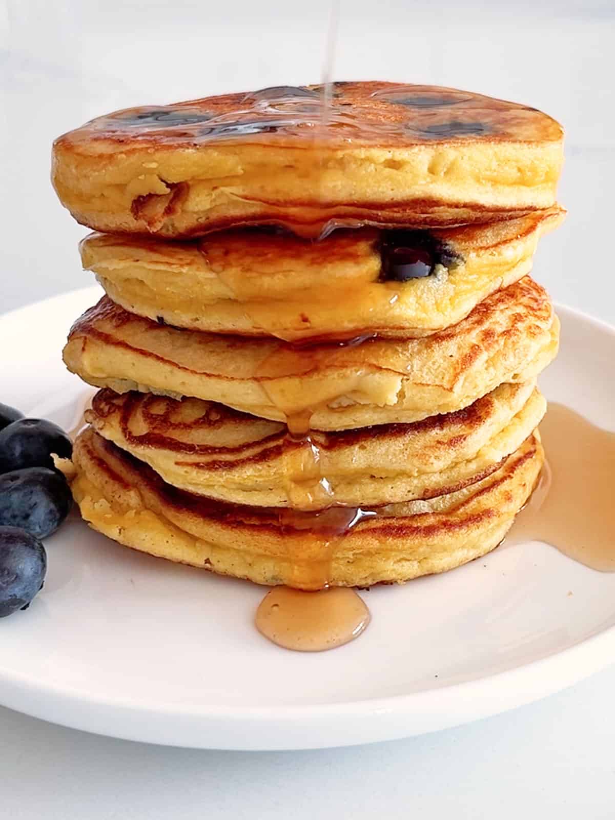 Coconut flour pancakes are drizzled with maple syrup.