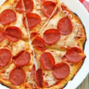 Coconut flour pizza crust is topped with cheese and pepperoni.