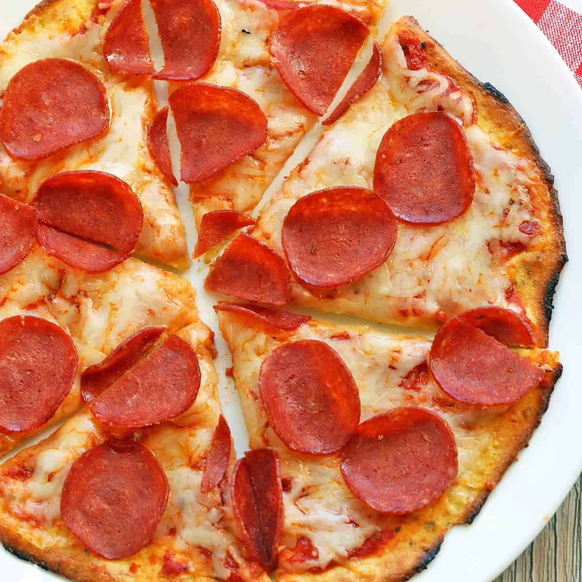 Coconut flour pizza crust is topped with cheese and pepperoni.