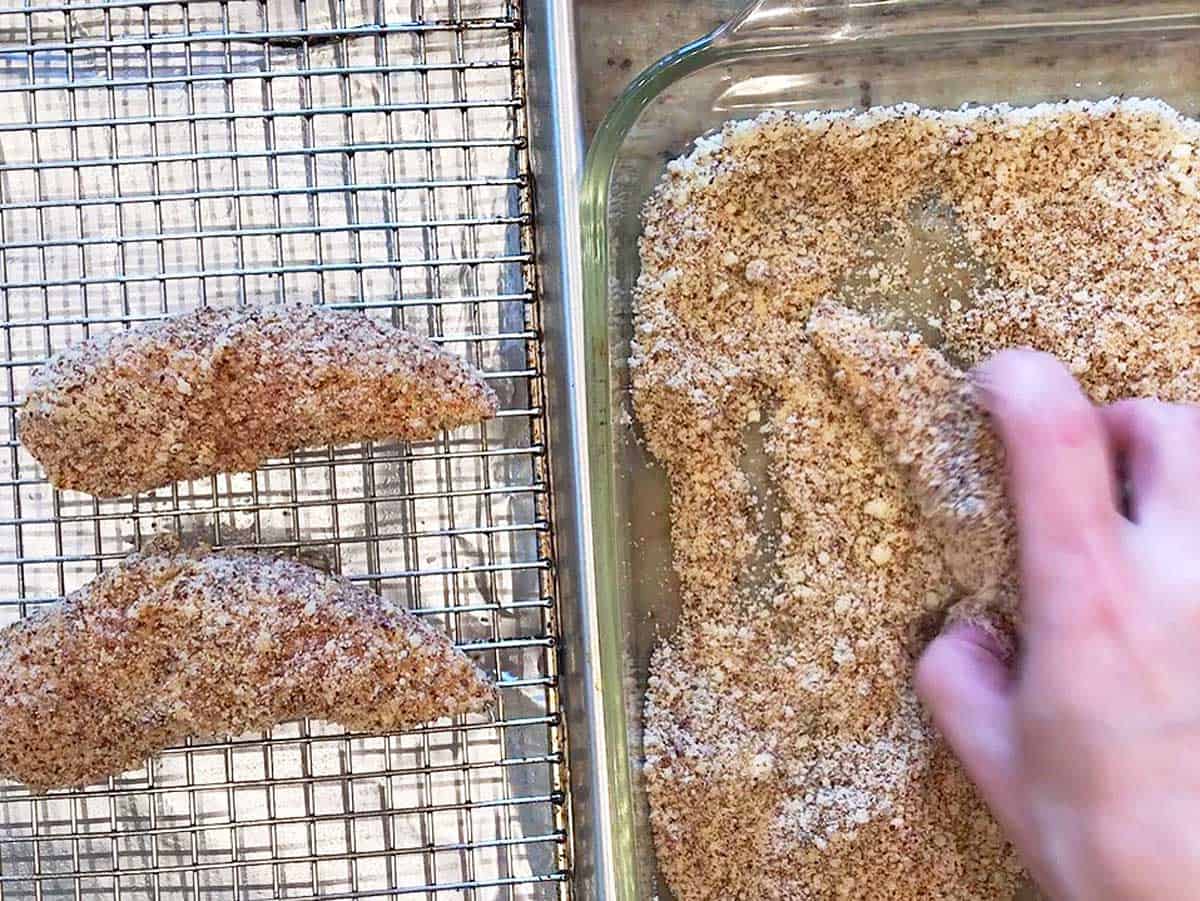 Dredging the chicken in the almond meal-parmesan mixture.