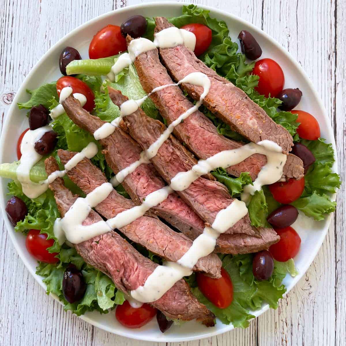 Leftover flank steak used in a salad with lettuce, tomatoes, and olives.