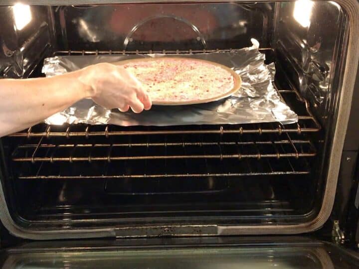 Placing the ground beef crust in the oven.