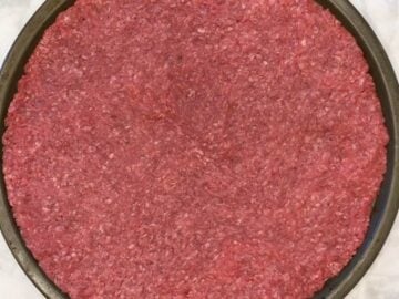 The ground beef covers a pizza pan.