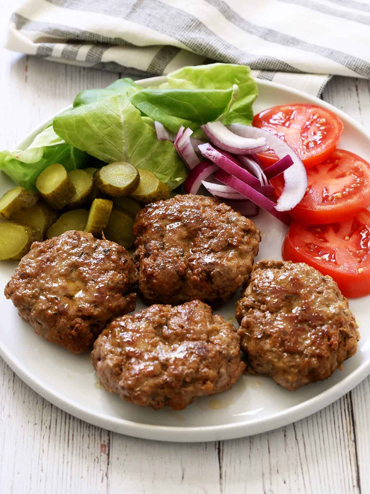 Pork burgers are served with vegetables.