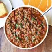 Pumpkin chili is served in a white bowl with cornbread.