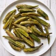 Roasted okra is served on a white plate.