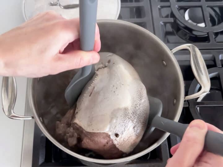 Flipping the tongue with two wide spatulas.