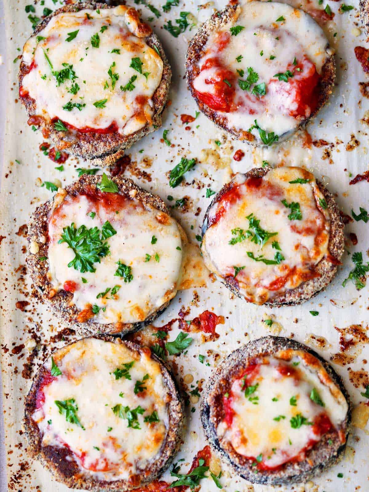 Keto eggplant parmesan is served on a parchment-lined baking sheet.