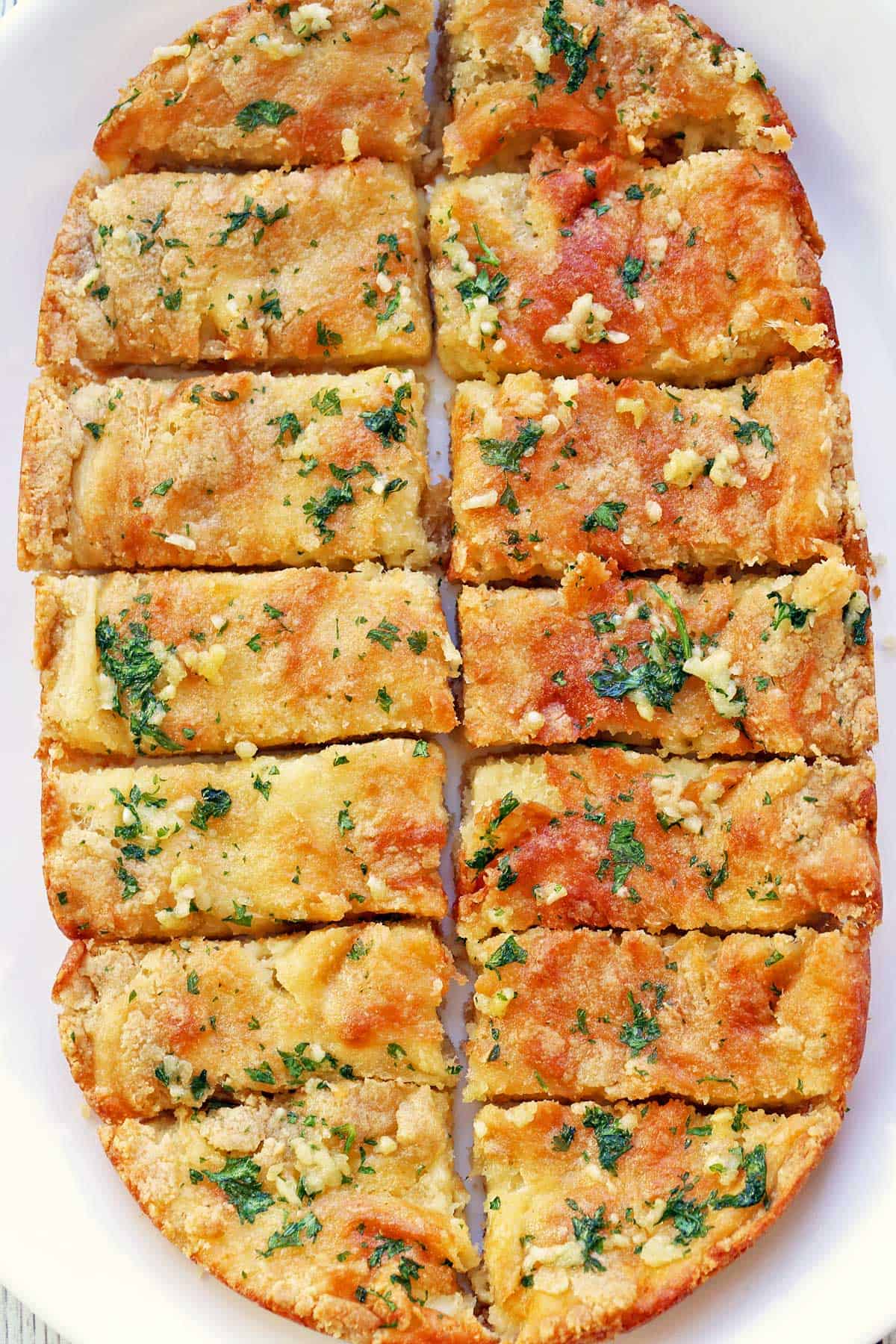 Keto garlic bread is served on a white platter.