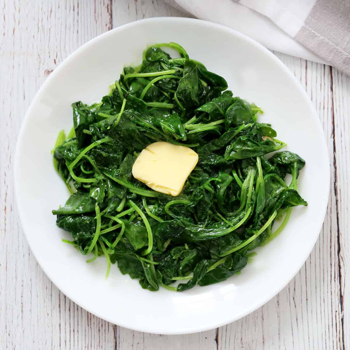 Sauteed kale is topped with butter.