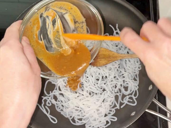Adding the sauce to the noodles.