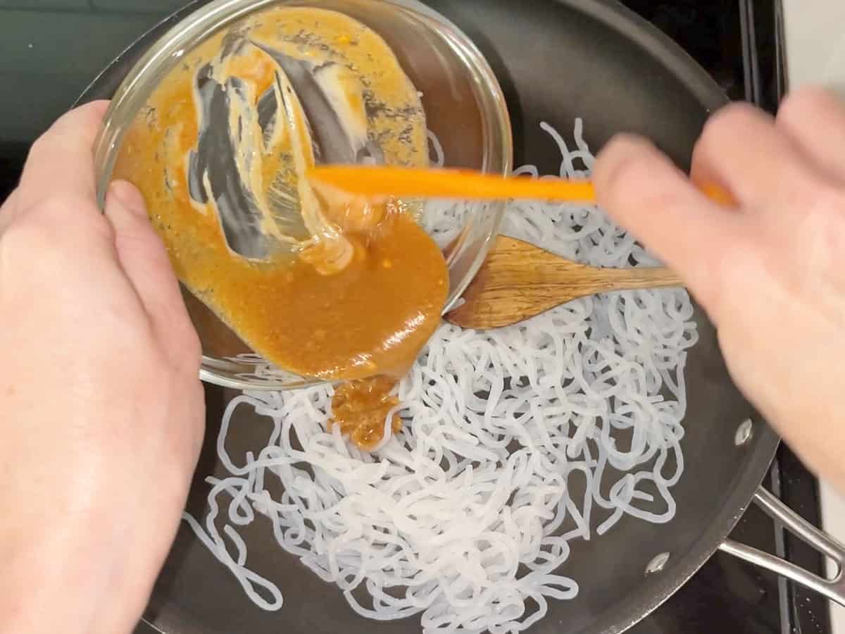 Adding the sauce to the noodles.