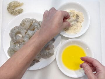 Dredging a shrimp in the parmesan mixture.
