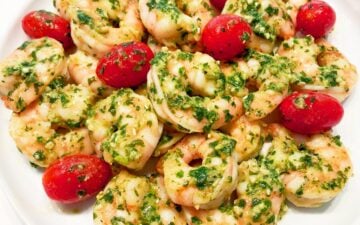 The shrimp and tomatoes are served on a white plate.