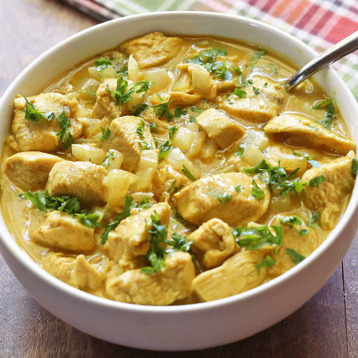 Thai chicken curry is served in a white bowl with a spoon.