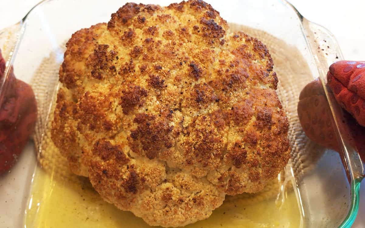 Roasted whole cauliflower in a baking dish.