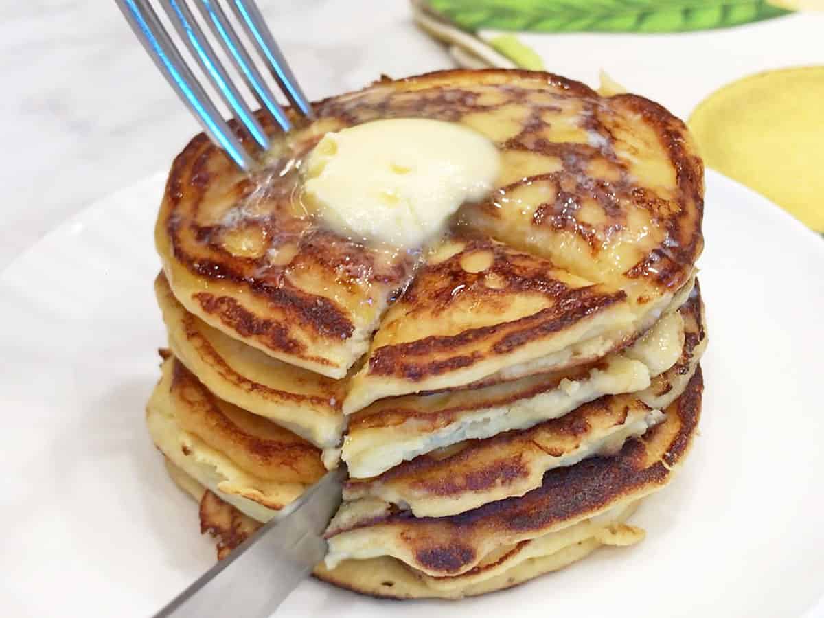 Cutting a stack of pancakes with a knife and fork.