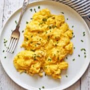 Fluffy scrambled eggs are served with a fork.