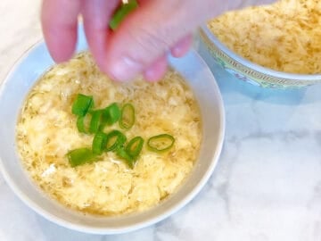 The soup is garnished with chopped scallions.