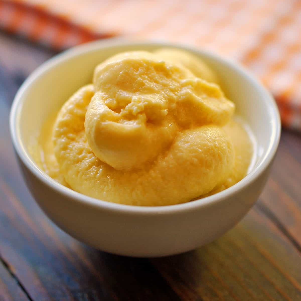 Mango frozen yogurt soft-serve in a white bowl.