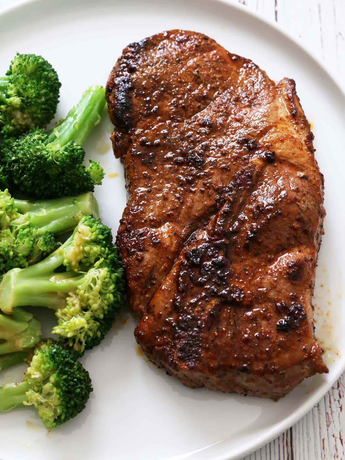 A pork steak is served with broccoli.
