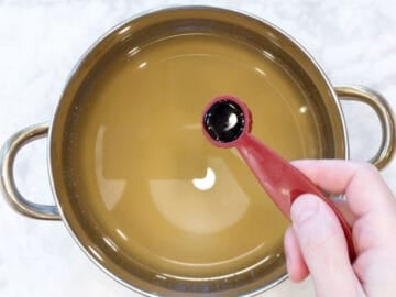 Adding soy sauce to the broth.