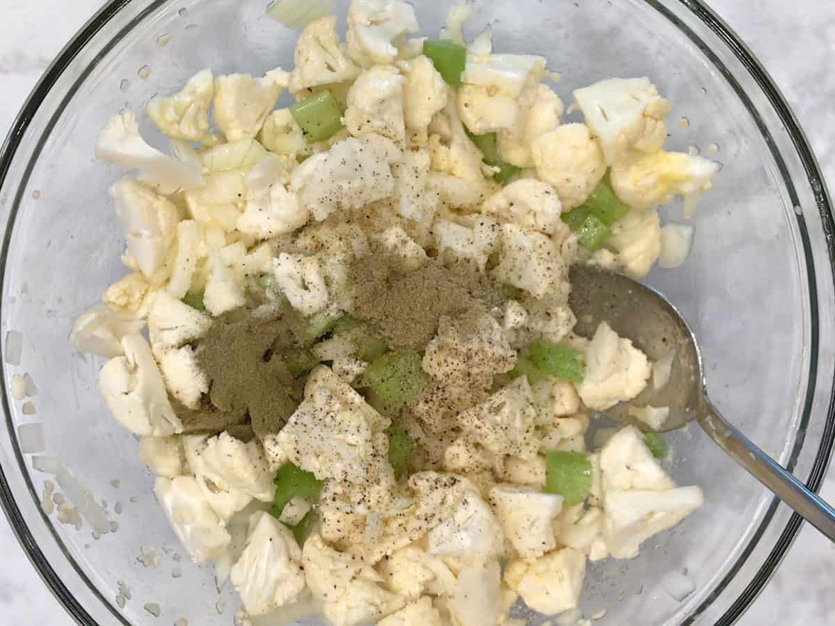 Veggies, melted butter, and spices in a bowl.