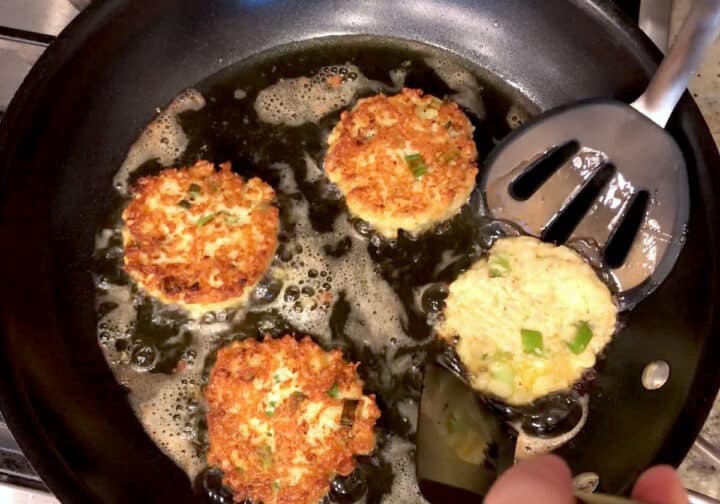 Flipping the fritters in the skillet.