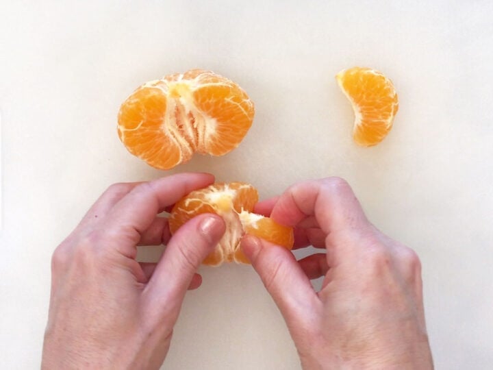 Dividing the orange into segments.