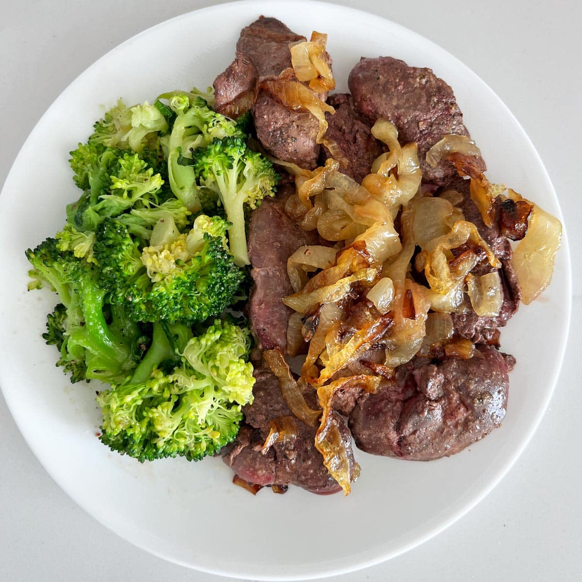 Chicken livers are served with steamed broccoli.