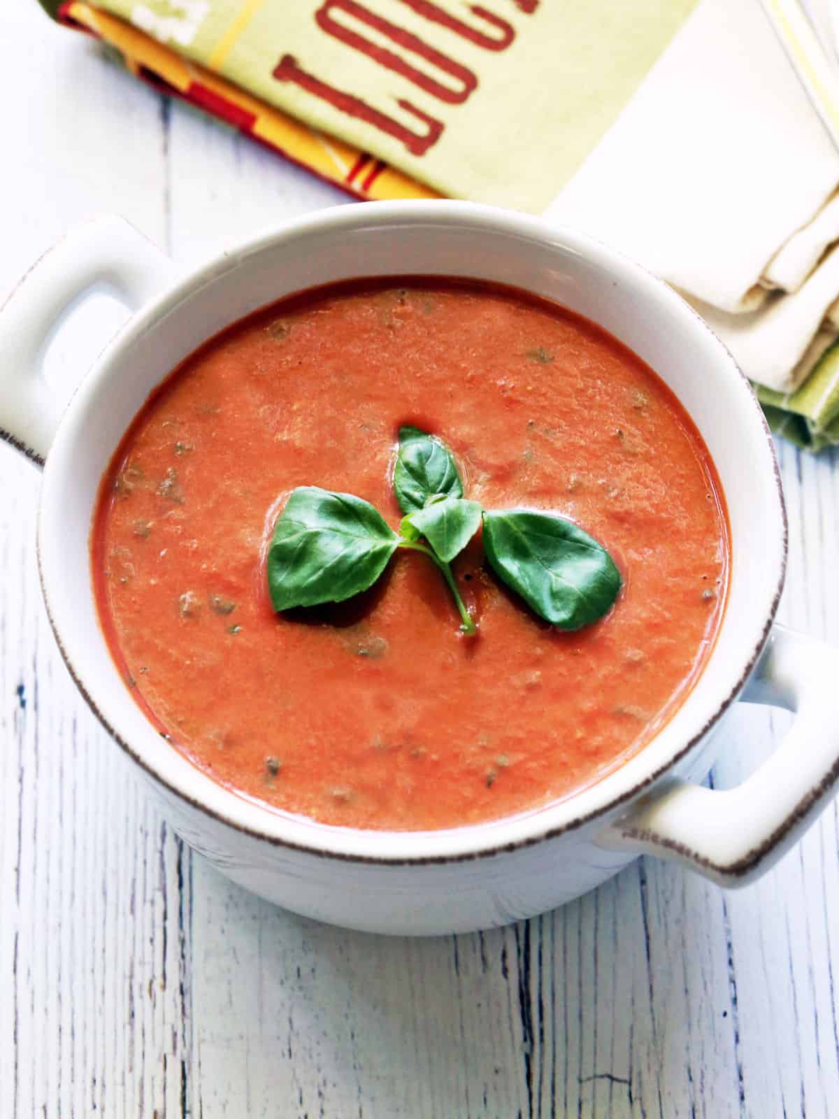 Cold tomato soup is served in a white bowl.