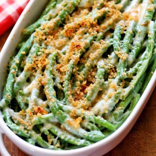 Keto green bean casserole is served in a white baking dish with a red napkin in the background.