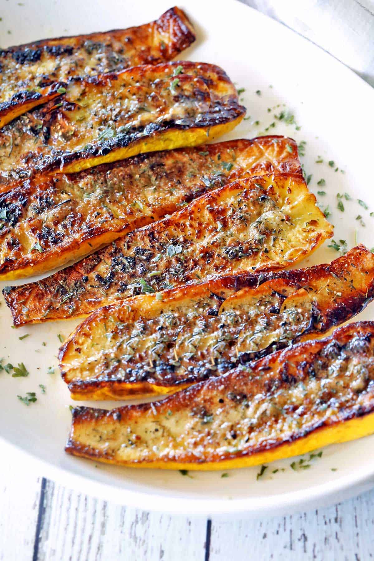 Roasted yellow squash is served on a white platter.
