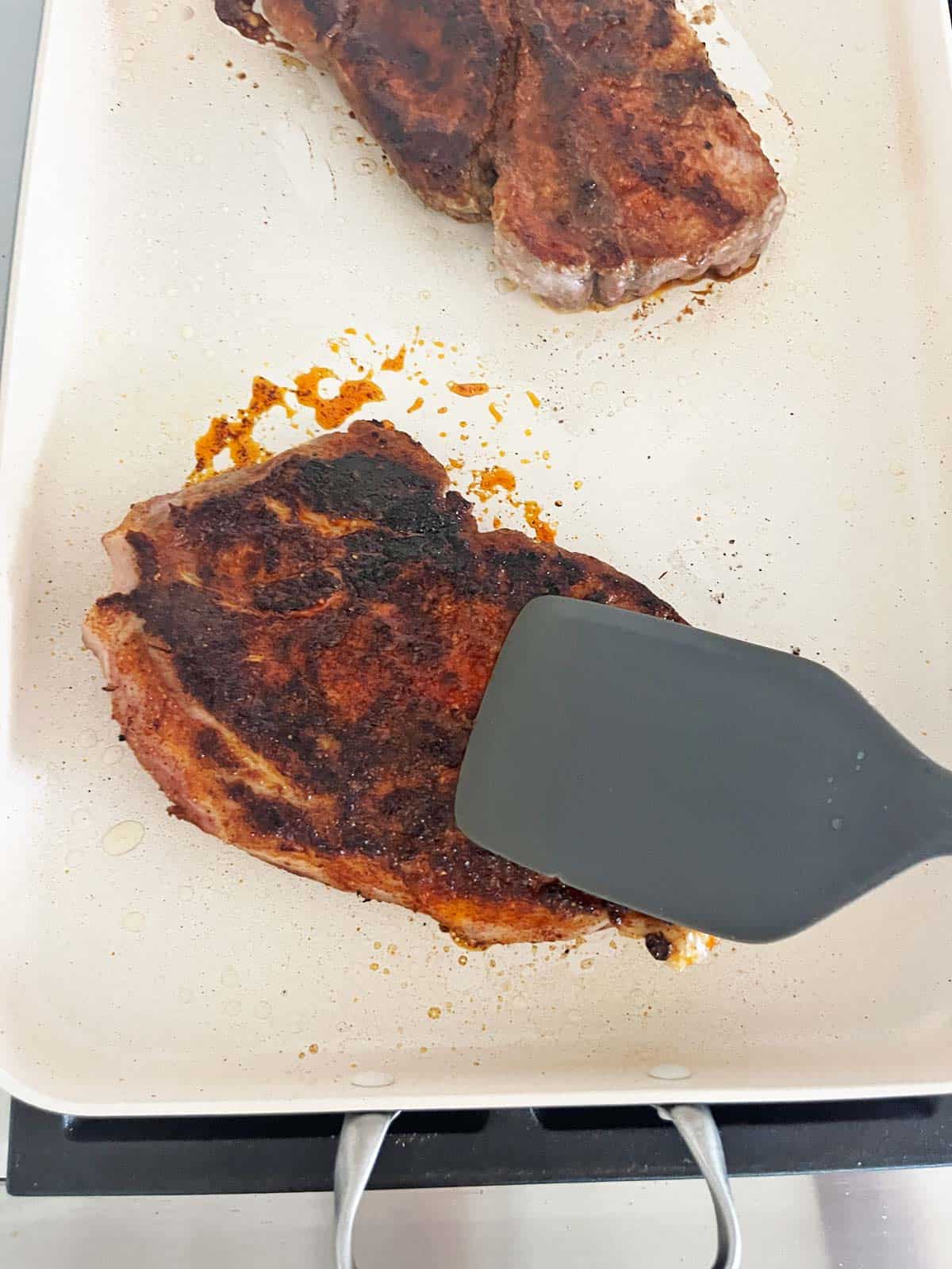 Pressing on the steak with a spatula.