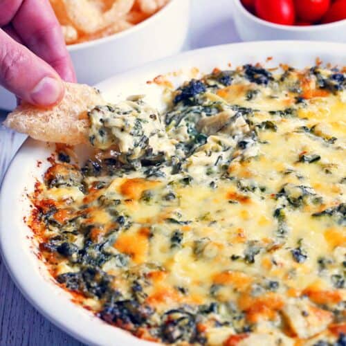 Spinach artichoke dip is scooped with pork rinds.