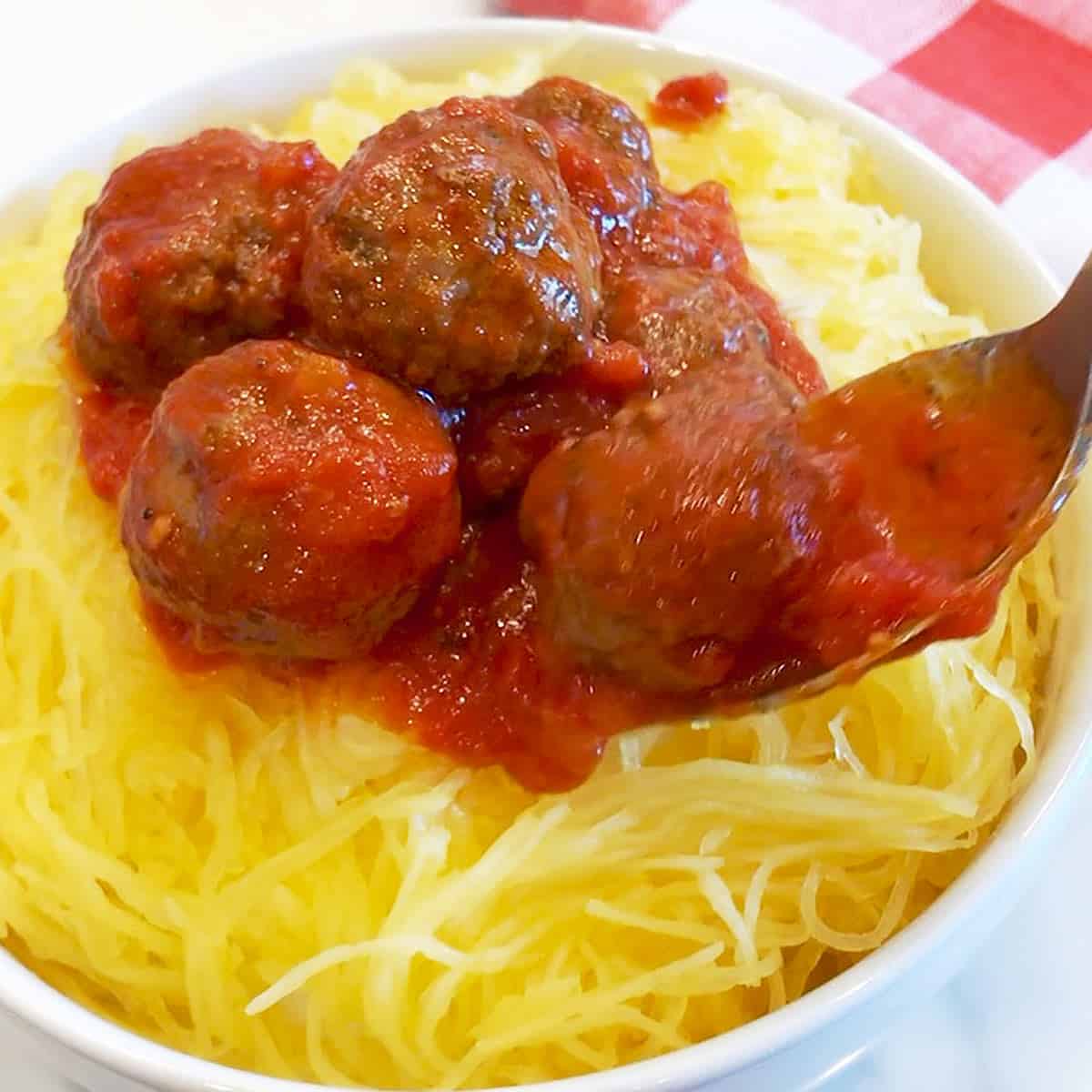 Topping the spaghetti squash with the meatballs and sauce.