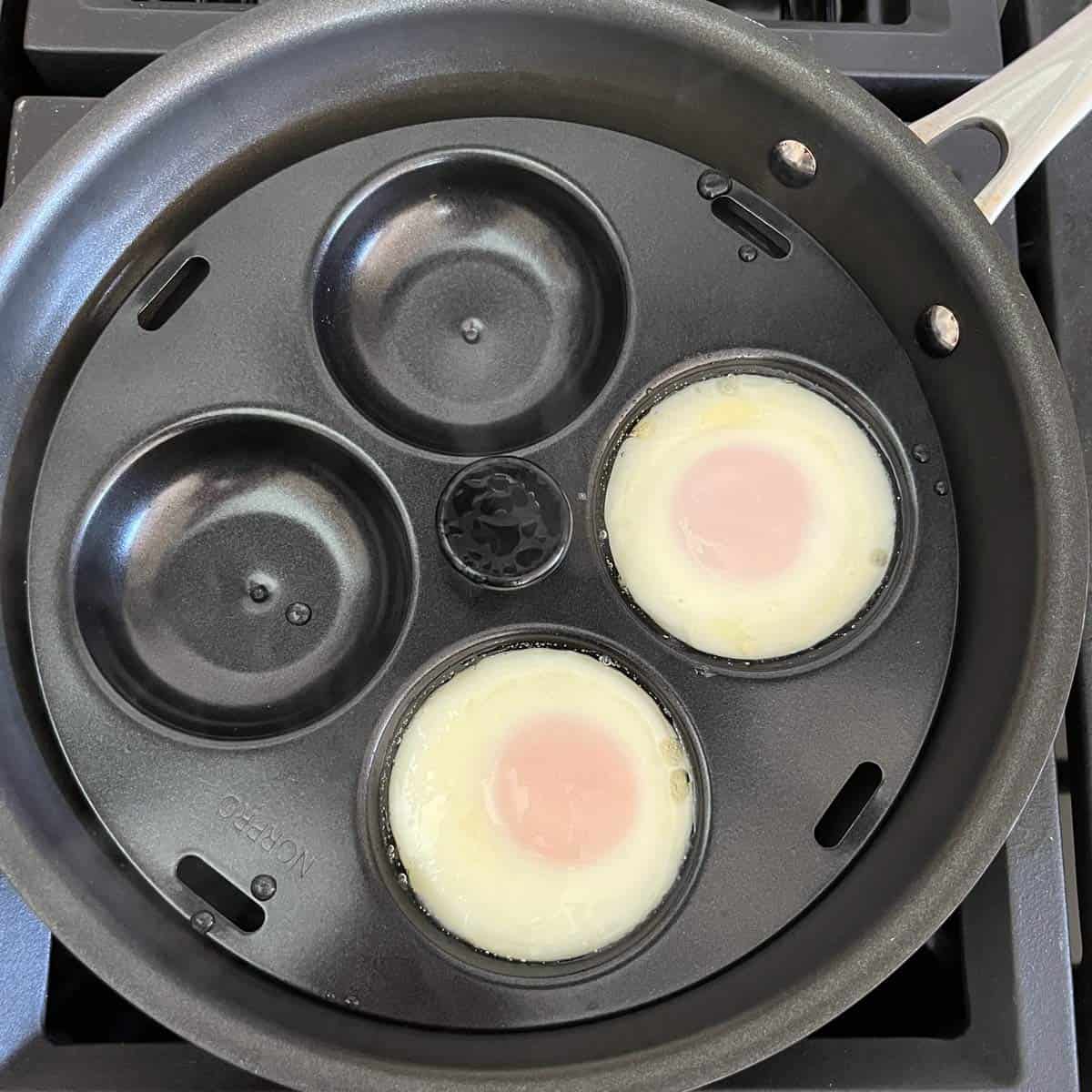 Two eggs in a stovetop poacher.