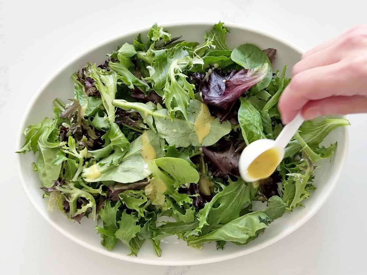 Dressing the mixed greens with half the vinaigrette.