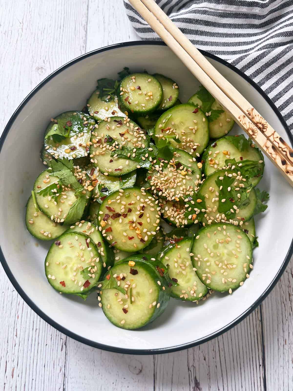 Asian cucumber salad is served with chopsticks.