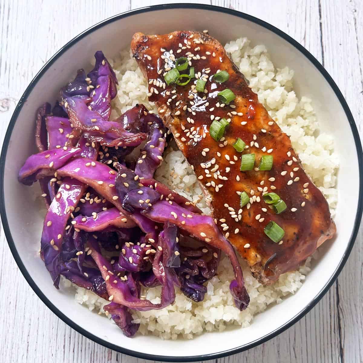 Cauliflower rice is topped with teriyaki salmon and red cabbage stir-fry.