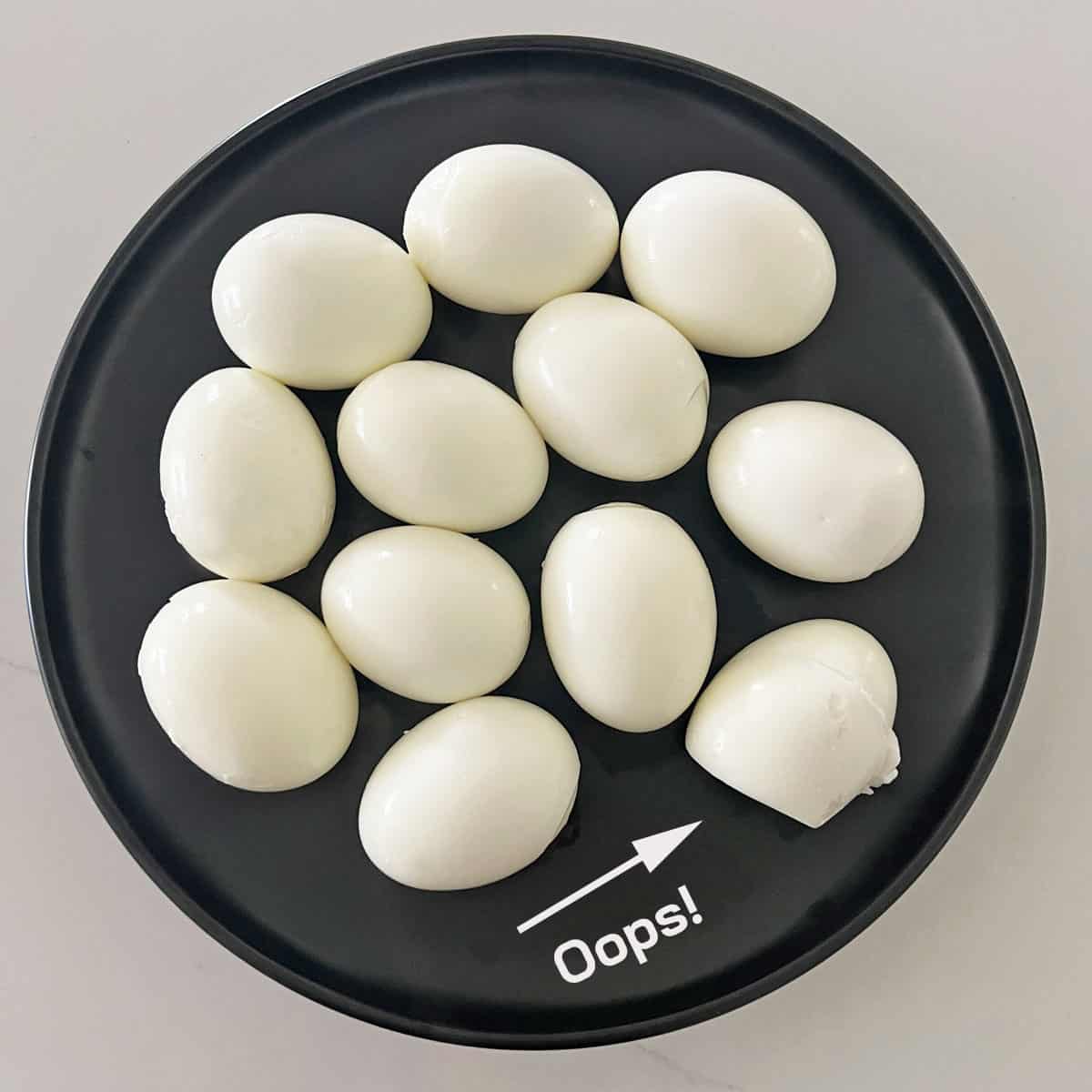 A hard-boiled egg that cracked when lowered into the boiling water is shown on a plate alongside the other eggs.